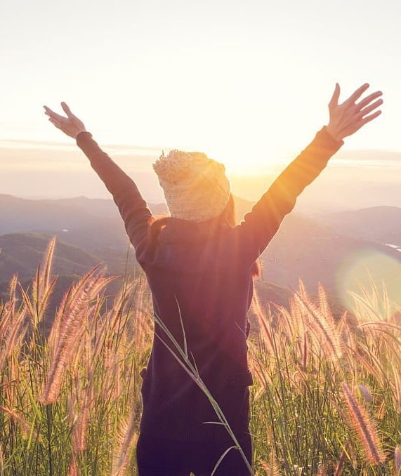 Activities -Carefree Happy Woman Enjoying Nature on grass meadow on top of mountain cliff with sunrise. Beauty Girl Outdoor. Freedom concept. Len flare effect. Sunbeams. Enjoyment.